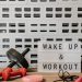 Fitness gear and motivational sign in home gym setup against a brick wall.